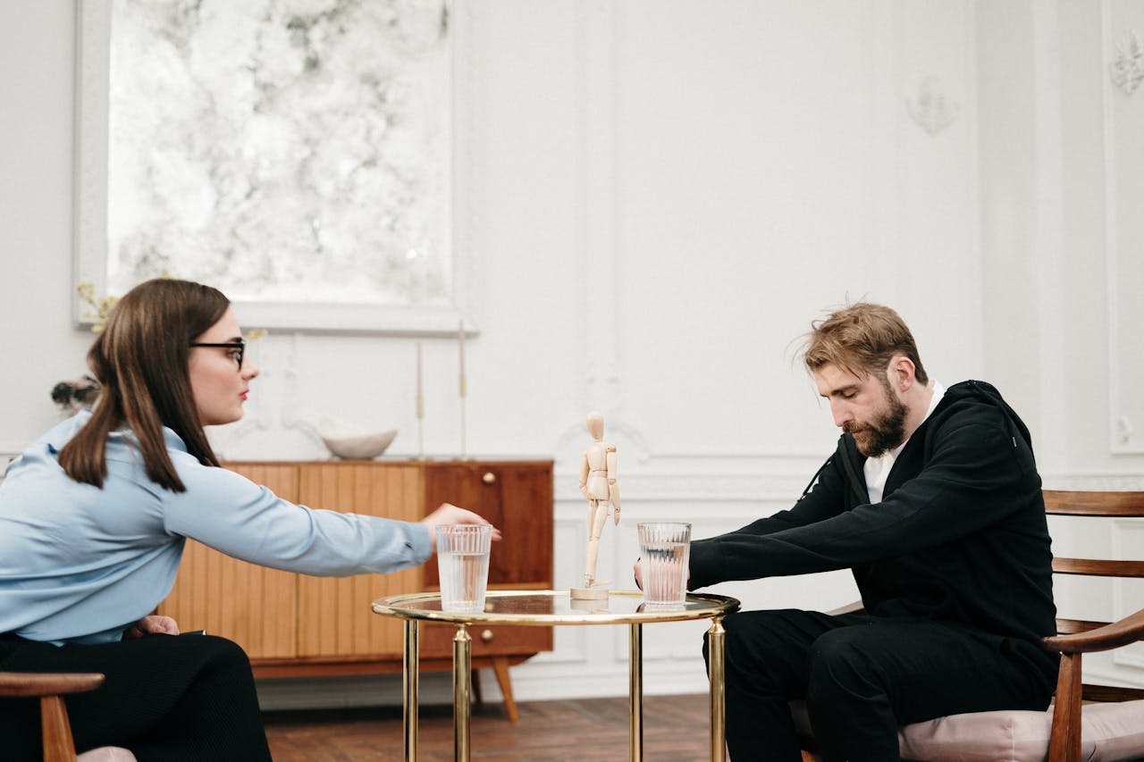 A man and woman engaged in a therapy session at a modern office, discussing emotions.